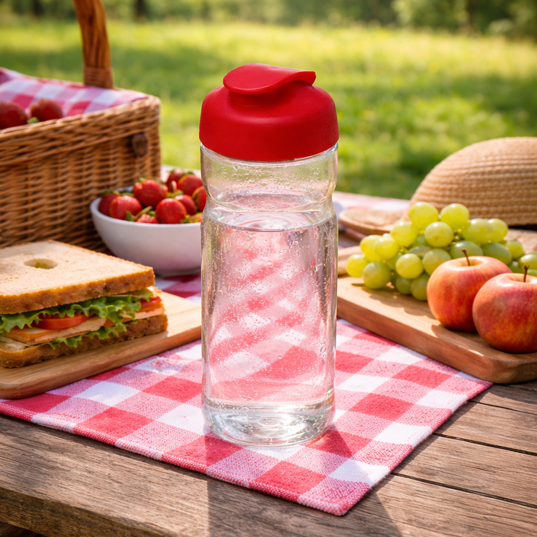red water bottle with flip lid on picnic setting