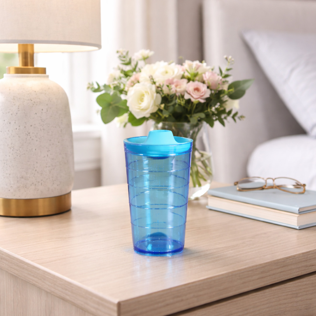 Blue spout in tumbler next to bedside with flowers